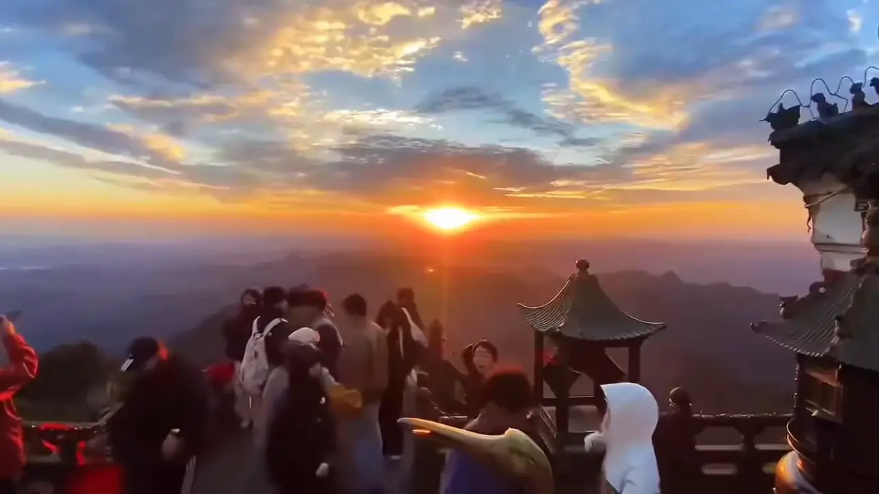 Crowds on the stone terrace of Wudang's Golden Summit watch the sun rise over a sea of clouds, bronze incense burners and temple eaves in the foreground.