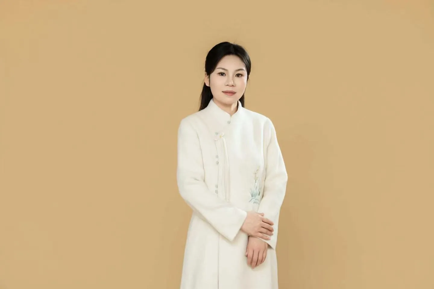 Chongmin in a white embroidered robe, hands folded, against a plain tan background