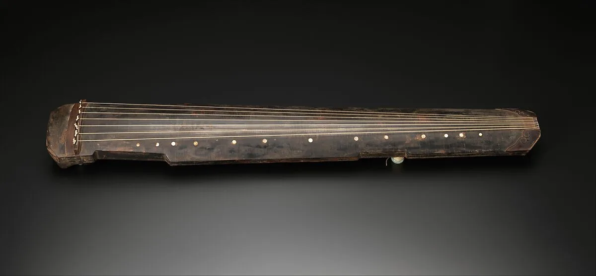 Détail d’un guqin en laque sombre daté de 1634, avec cordes et repères clairs.