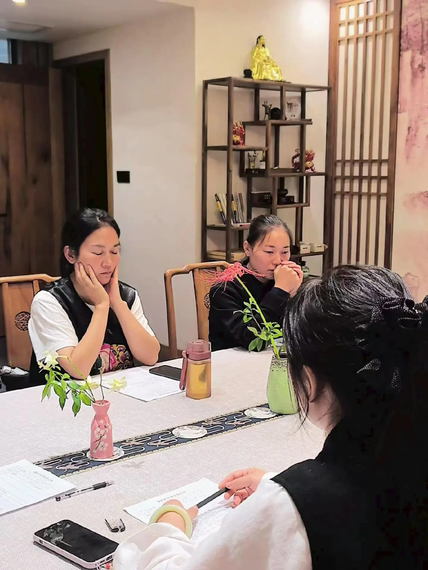 Deux participantes se reposent à table, les yeux fermés et les mains près du visage.